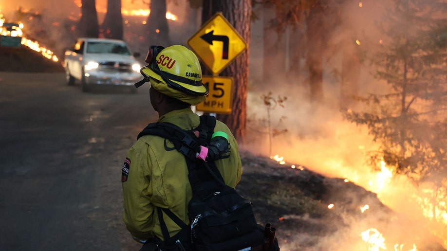 firefighter in road near flames and smoke