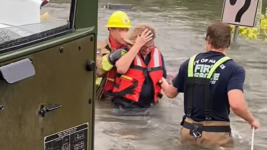 firefighters leading woman to safety through flood