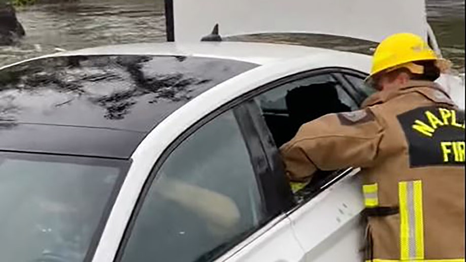 Firefighter breaking window to car trapped in flood