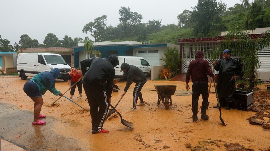 muddy road with people cleaning debris