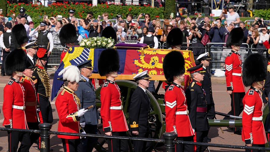 Guards in red uniforms stand around Queen Elizabeth's coffin
