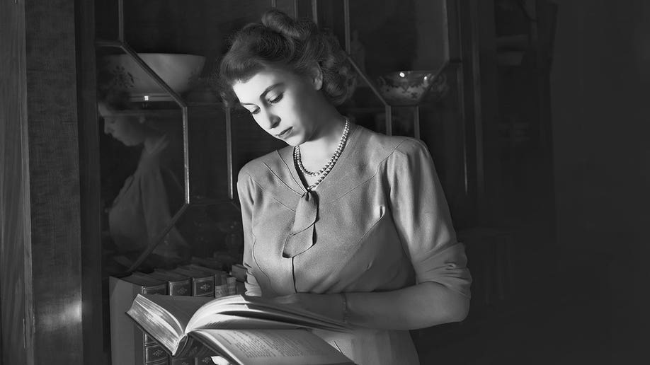 Black and white photo of young Queen Elizabeth reading inside