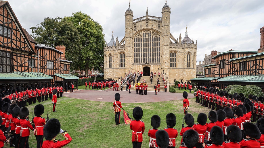 Guards in red uniforms carry Queen Elizabeth's casket into St. George's Chapel