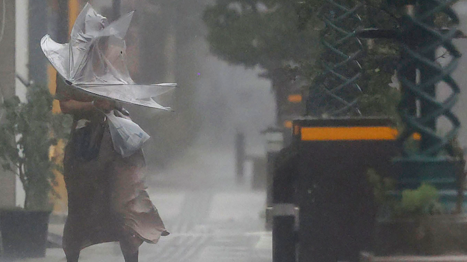 A woman makes her way through the strong wind and rain