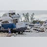 A man runs beside a battered boat in Fort Meyers during Hurricane Ian