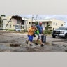 King Point resident Maria Esturilho is escorted by her son Tony Esturilho as they leave behind the damage from an apparent overnight tornado spawned from Hurricane Ian at Kings Point 55+ community in Delray Beach, Fla., on Wednesday, Sept. 28, 2022. ?(Carline Jean /South Florida Sun-Sentinel via AP)