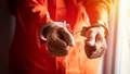 close up of prisoner's hands with handcuffs in orange jumpsuit at prison