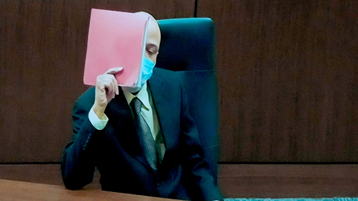 Darrell Brooks hides his face behind folders