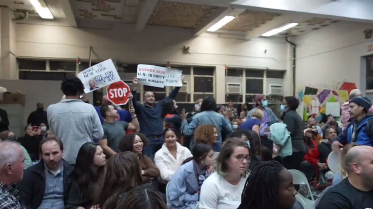 Protestors hold up signs during AOC's town hall appearance in Queens