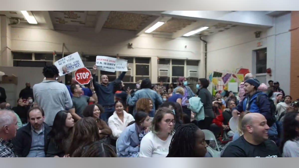 Protestors hold up signs during AOC's town hall appearance in Queens