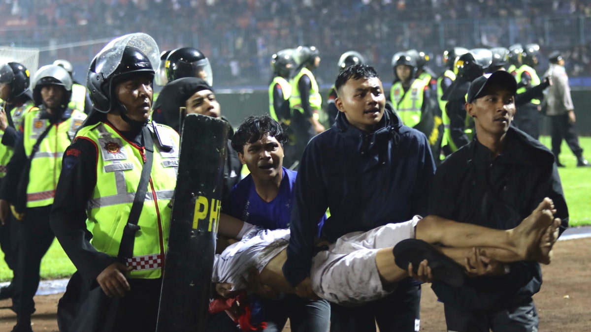 Soccer fans carry an injured man. Clashes between supporters of two Indonesian soccer teams in East Java province killed over 100 fans and a number of police officers, mostly trampled to death, police said Sunday.