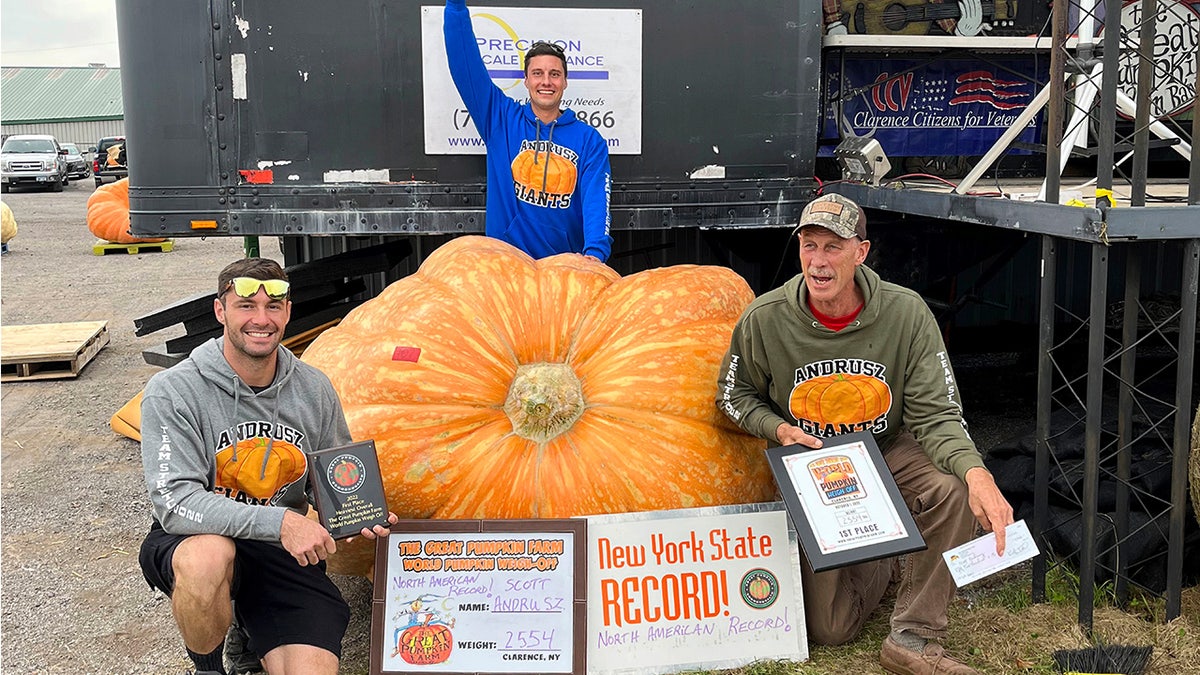 Emmett Andrusz, Steve Andrusz and Scott Andrusz pose near pumpkin