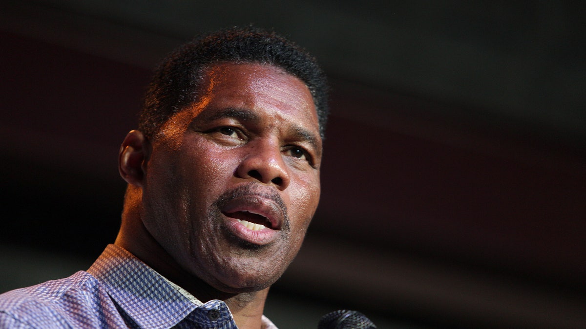 Herschel Walker wearing a purple shirt and speaking