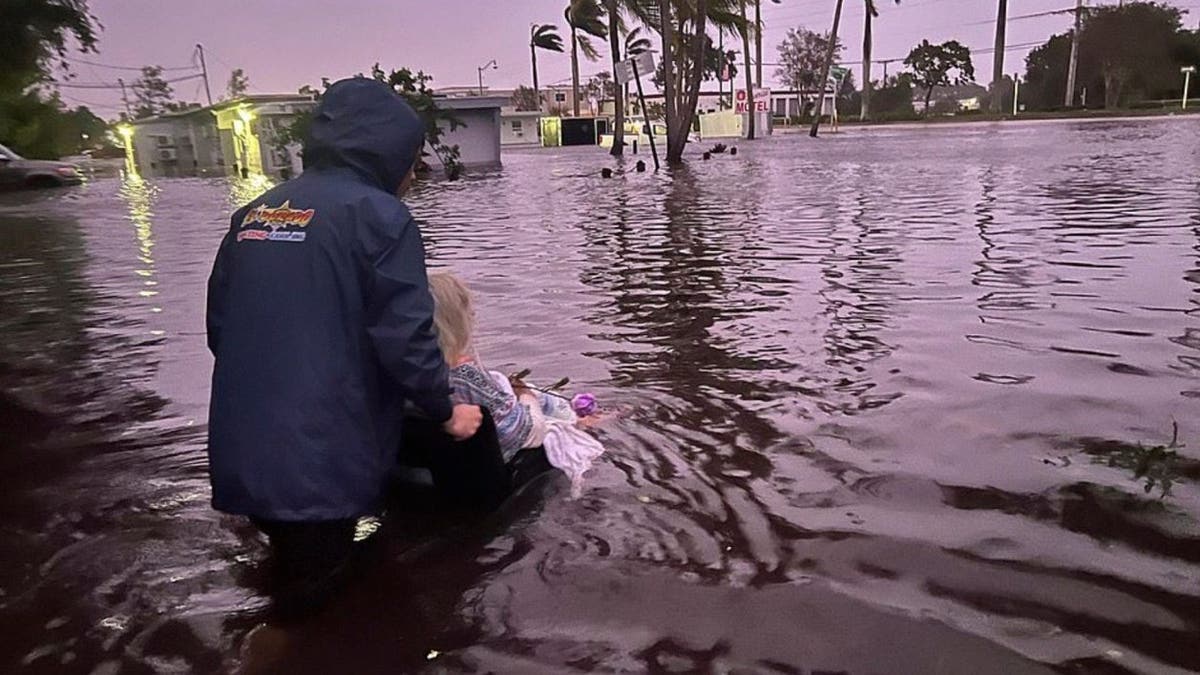 Man pushes woman in wheelchair through floodwater