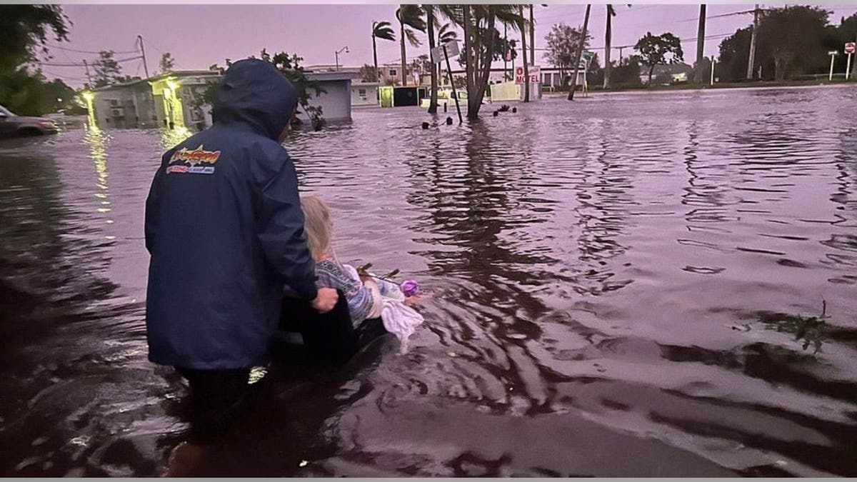 Man pushes woman in wheelchair through floodwater