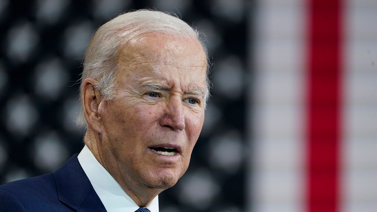 Joe Biden looks to his right with an American flag behind him