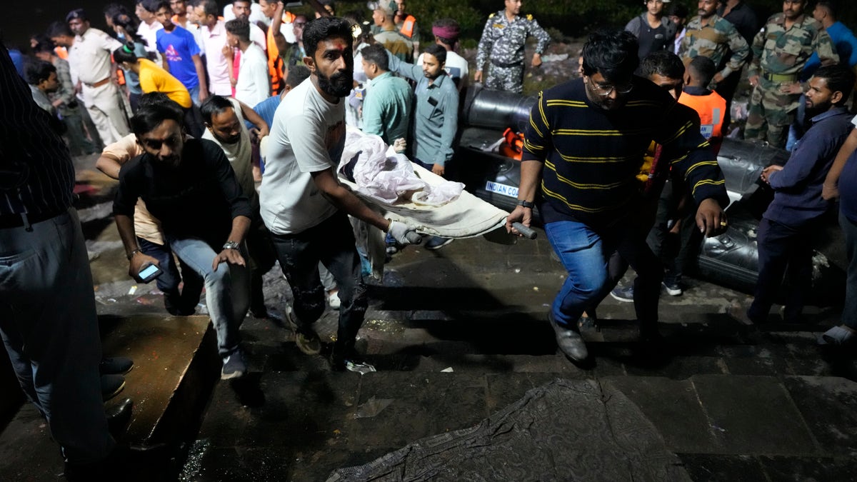 A victim is carried out of the water after the India bridge collapse