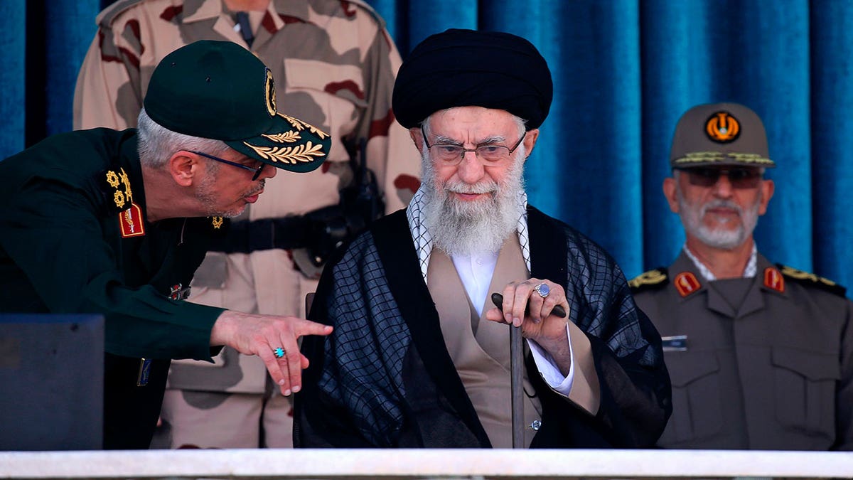 Supreme Leader Ayatollah Ali Khamenei speaks with an officer standing to his right