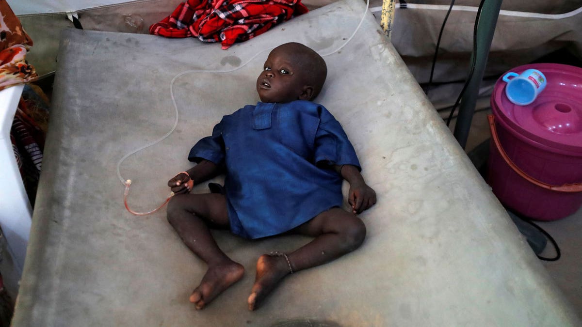 A cholera patient lies in bed receiving intravenous fluid