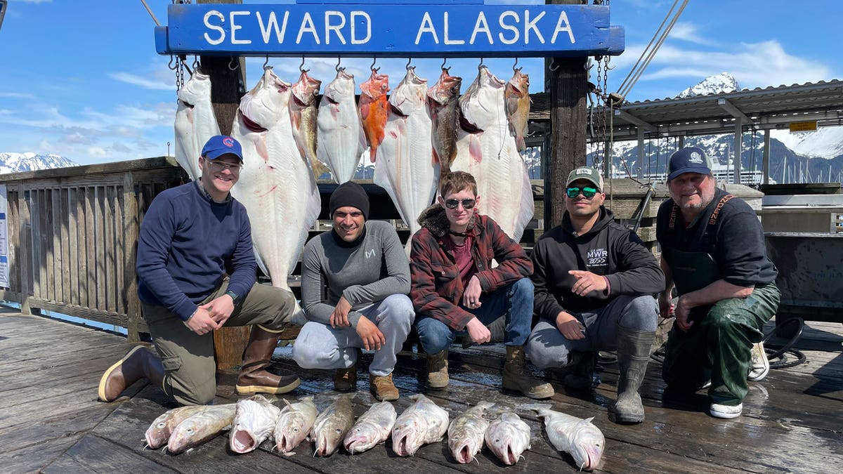 Men posing next to fish they caught