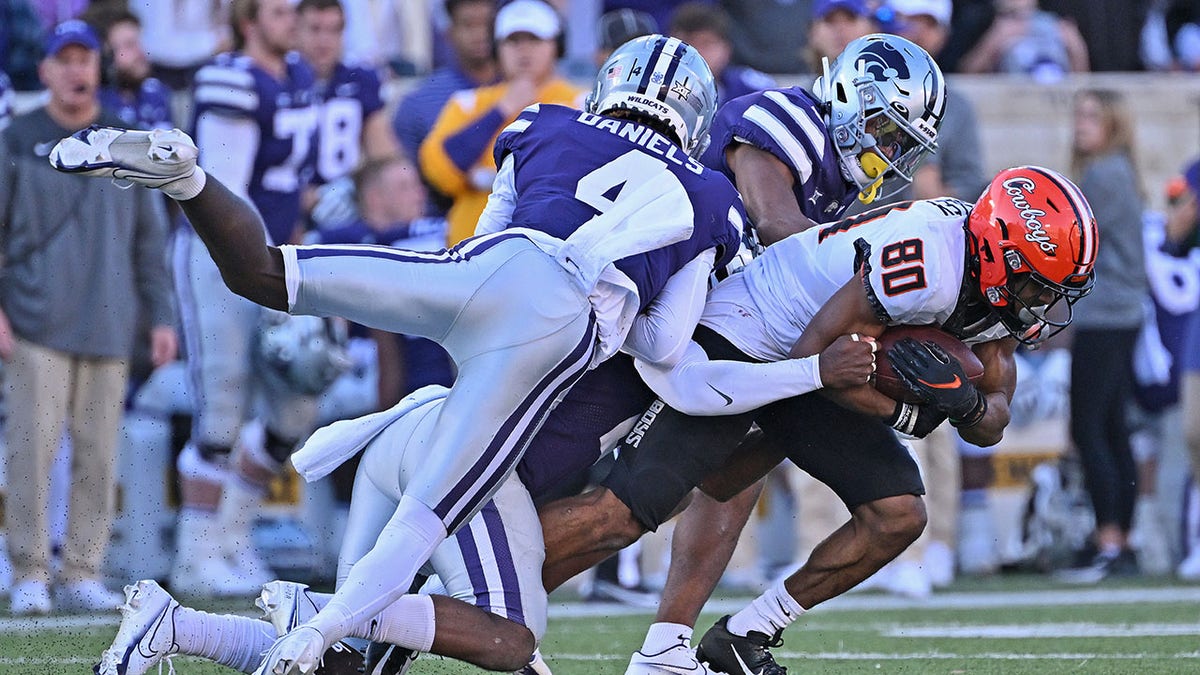 Two Kansas State players tackle an Oklahoma State player