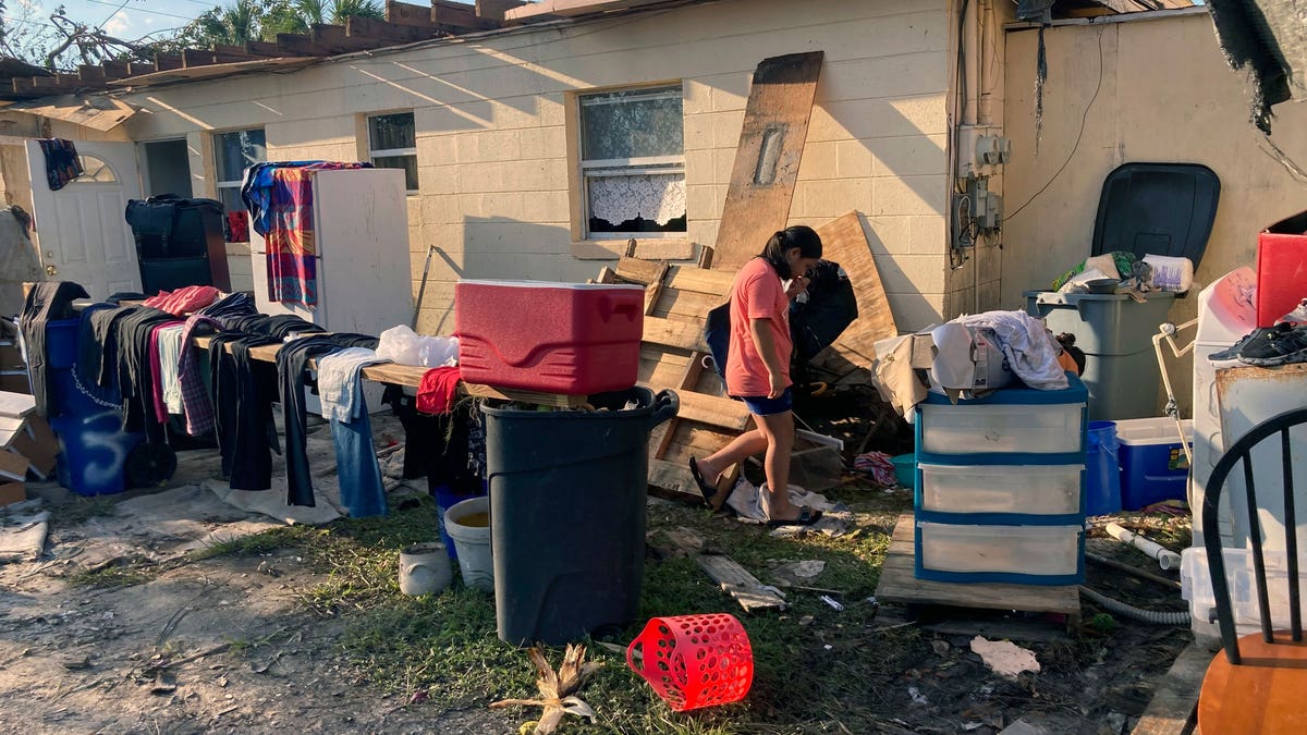 Woman walking through debris outside of her destroyed apartment