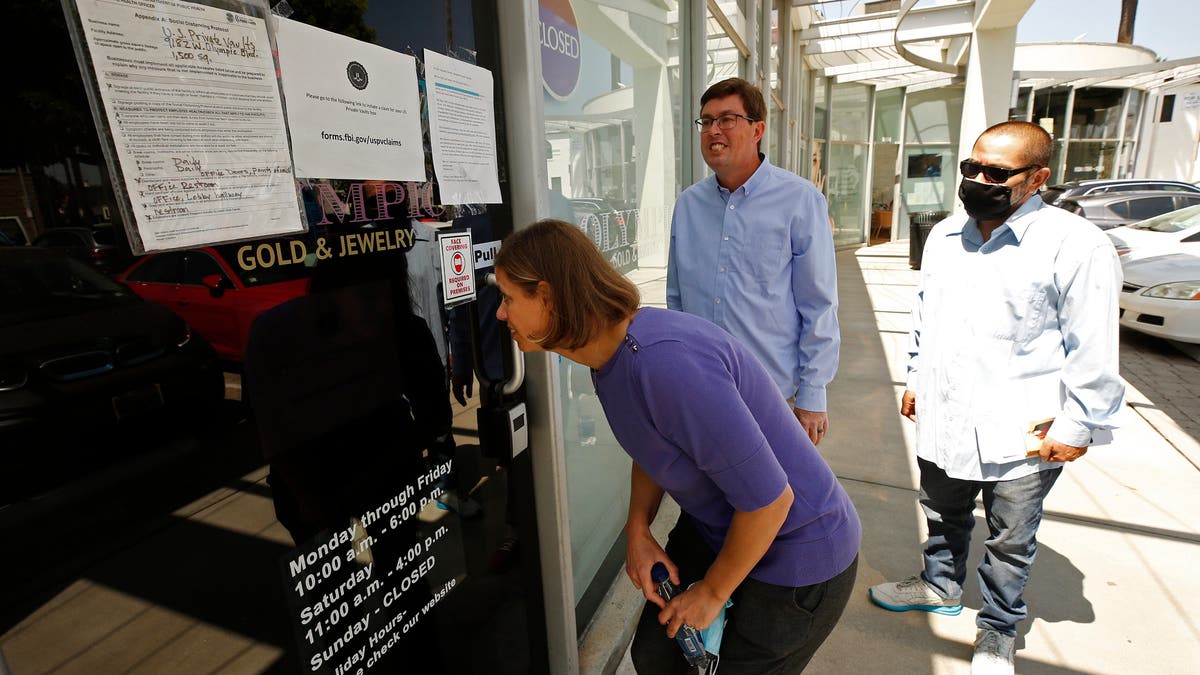 Plaintiffs Jennifer Snitko, husband Paul Snitko, and Joseph Ruiz, read sign outside US Private Vaults