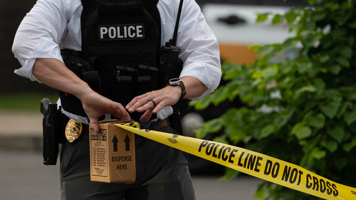 Police detective rolling out crime scene tape