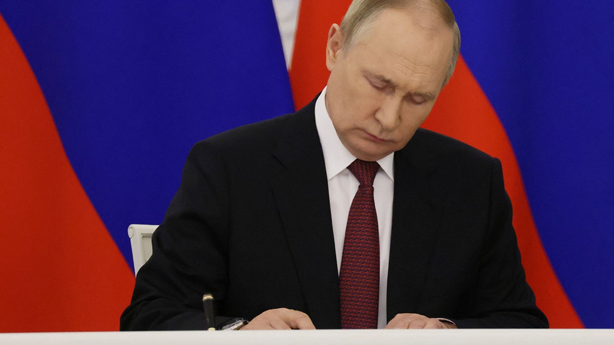 A photo of Putin signing the annexation of Ukraine regions