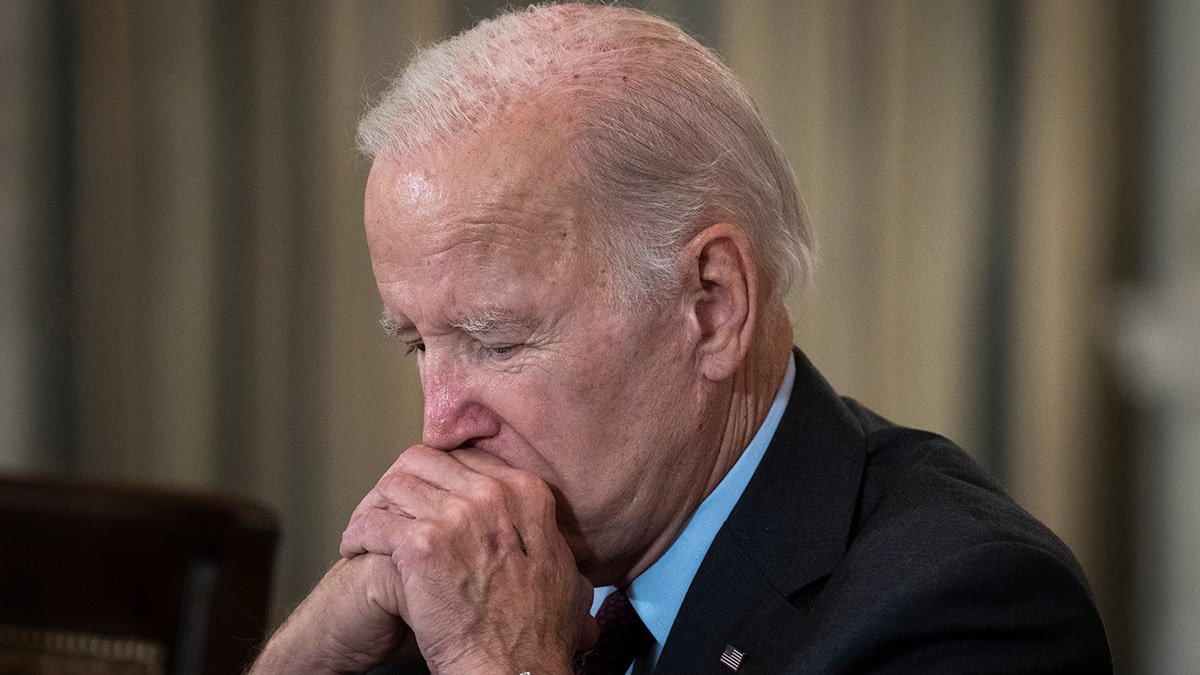 A photo of Joe Biden with his eyes closed, hands clasped together