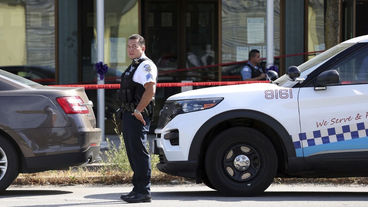 A Chicago police officer stands next to a police cruiser