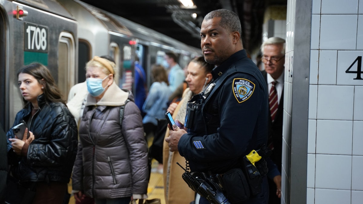 NYPD officer stands on a crowded subway platform
