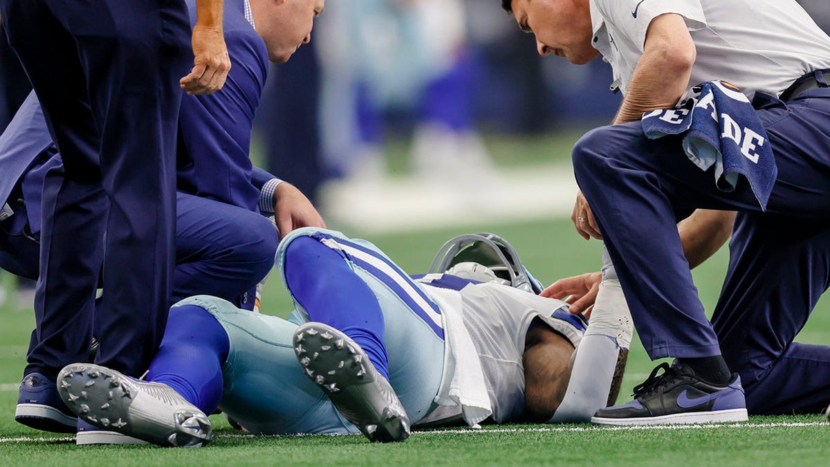 Dallas Cowboys running back Ezekiel Elliott lies on the ground while being attended by trainers during the game against the Detroit Lions on Oct. 23, 2022, in Arlington, Texas.