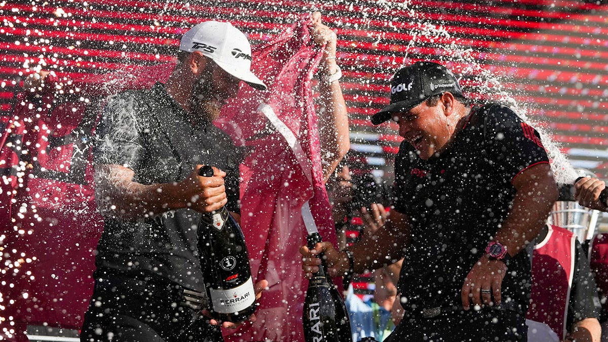 Dustin Johnson celebrates with Patrick Reed on stage