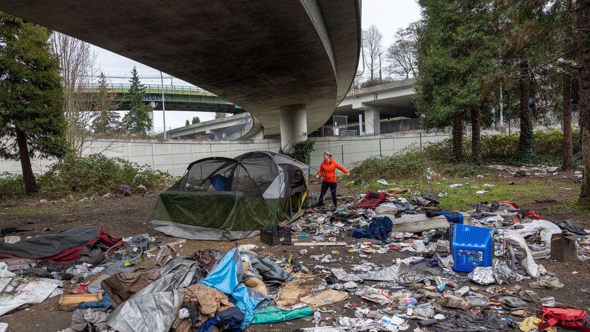 homeless camp beneath overpass strewn with garbage
