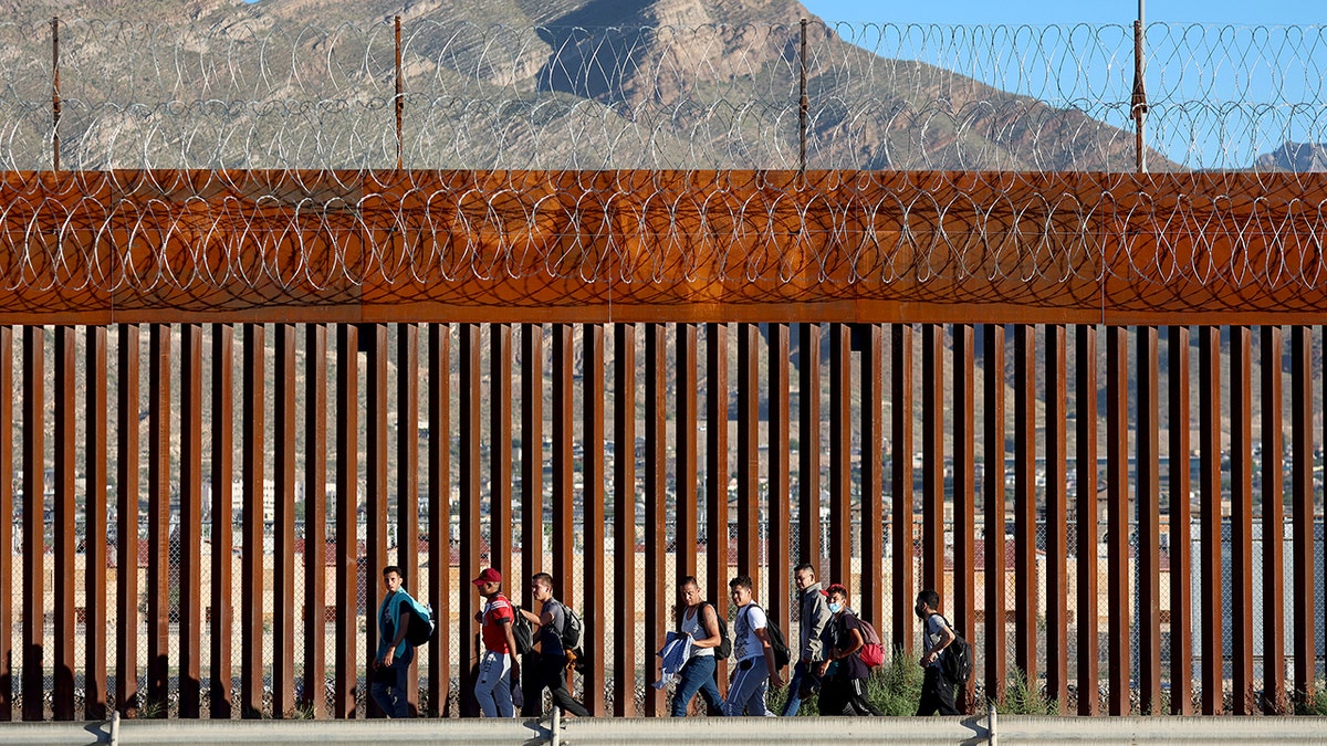 migrants by texas border wall