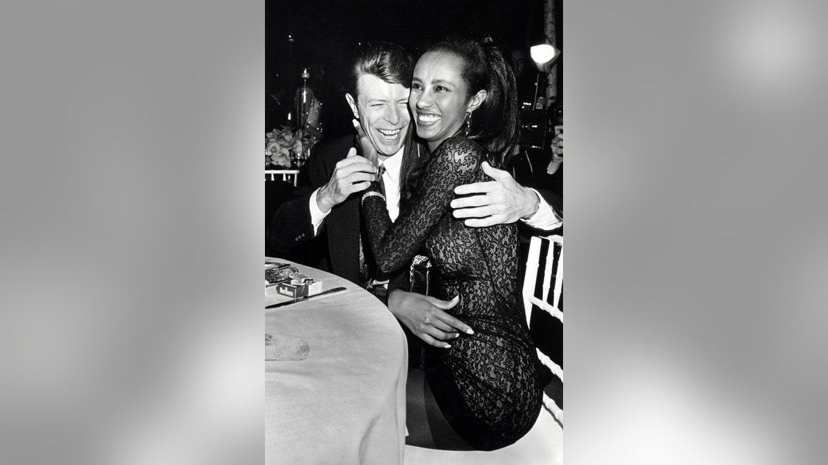 David Bowie and Iman hugging in a black and white photo