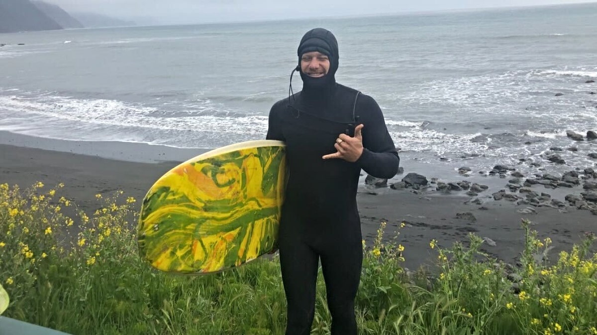 Michael Trainor holds a surf board