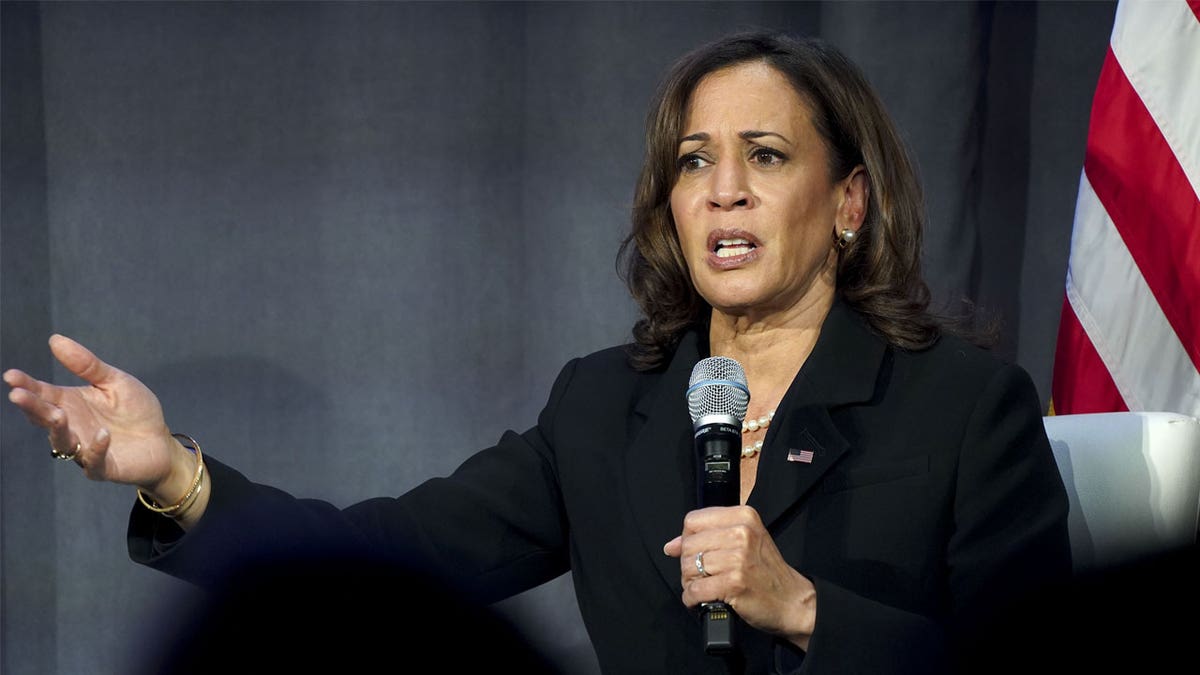 Kamala Harris holding mic with right arm stretched