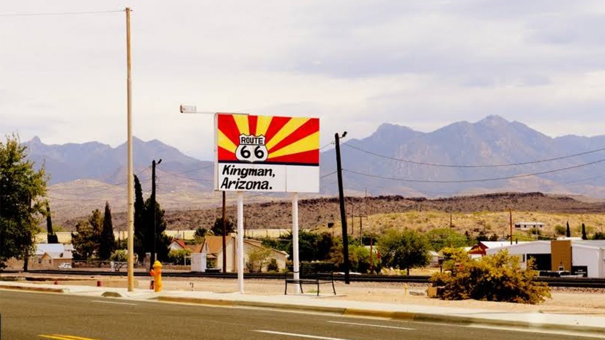A Kingman, Arizona, sign with the desert and mountains in the background