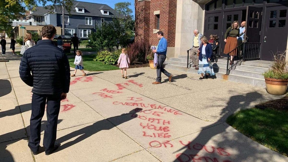 Parishoners leaving church via graffiti-covered sidewalk