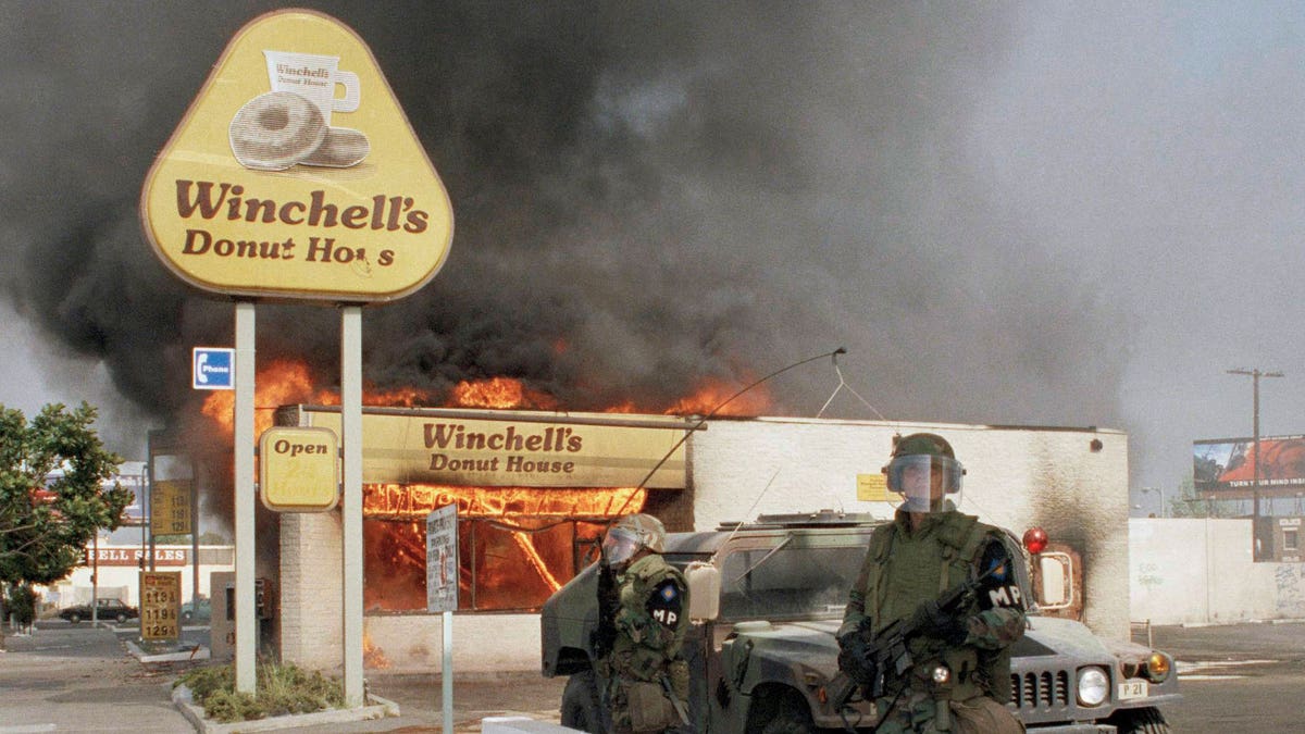 Two National guardsmen stand guard outside a burning donut shop