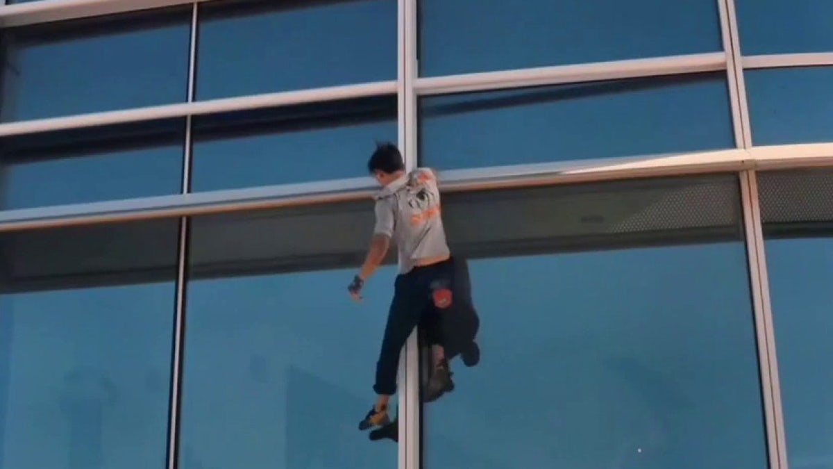 Maison Des Champs hands from the building railing as he climbs a 1,070-foot tower