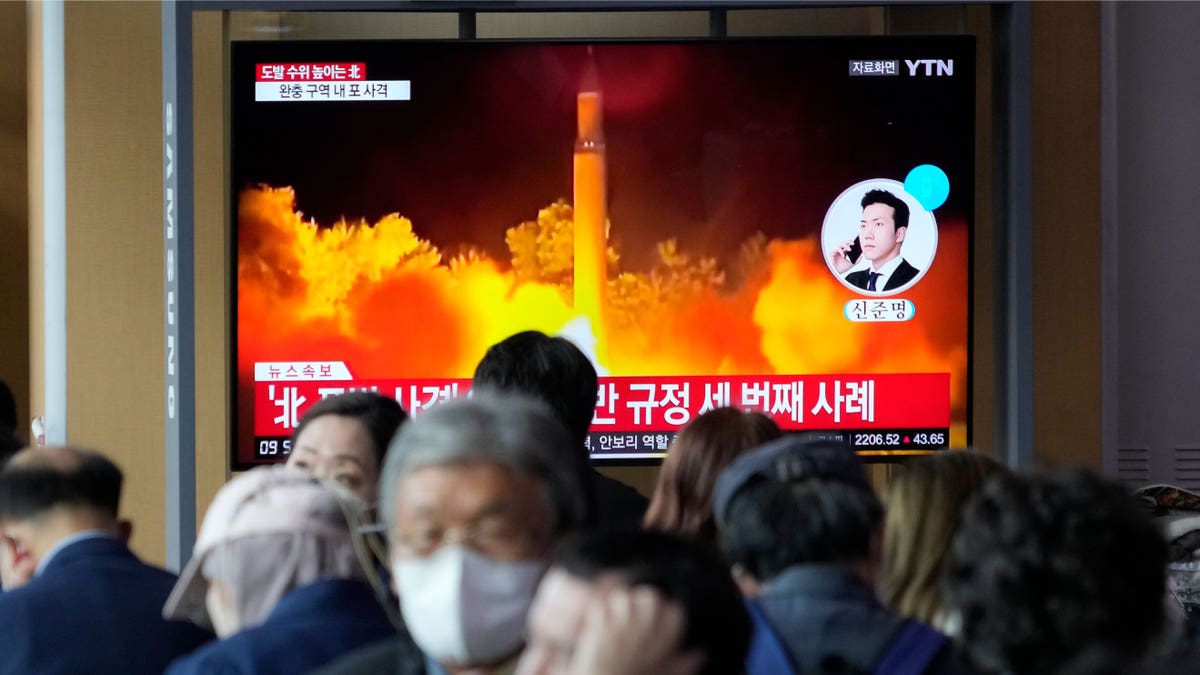 People watching a tv screen showing a missile launch in North Korea