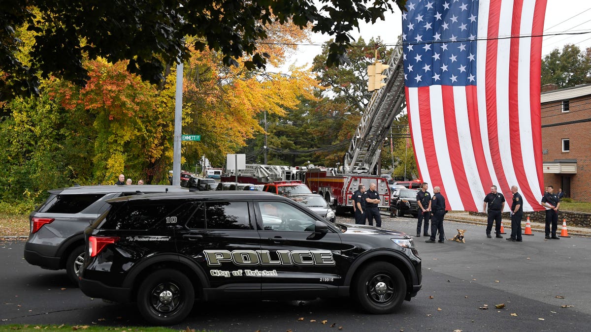 Police unit in the foreground as officers stand next to an American flag in the background