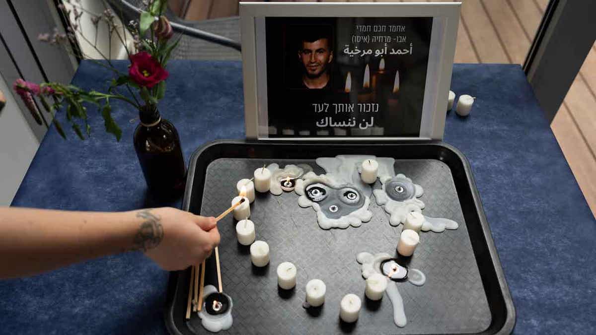 A volunteer lights a candle during a vigil