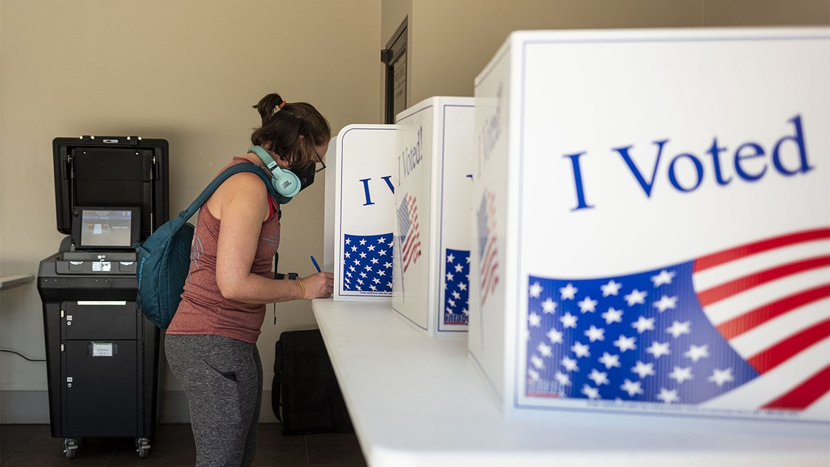 woman with backpack, headphones voting on election day