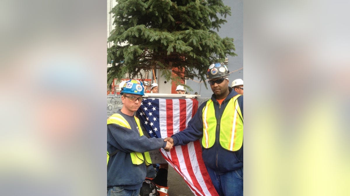 Tommy Bailey shaking hands with a man in front of an American flag