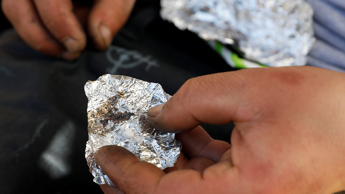 Man holding a piece of foil with synthetic fentanyl 