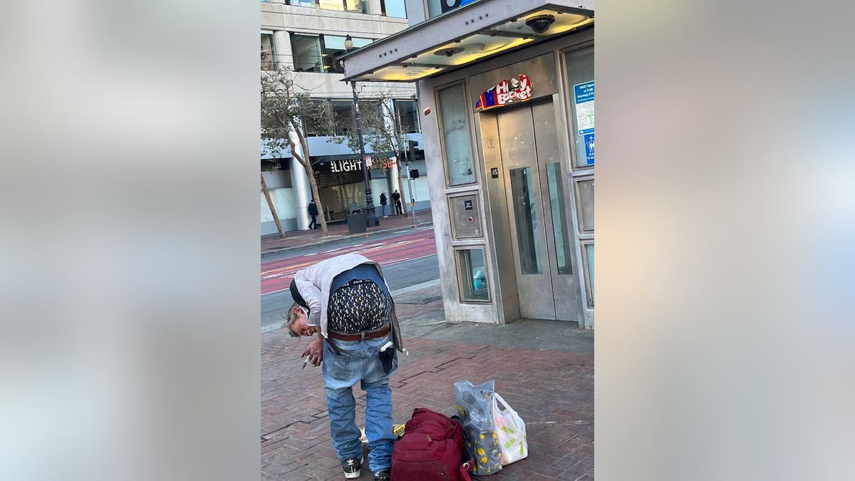 Homeless man hunched over in front of the elevator